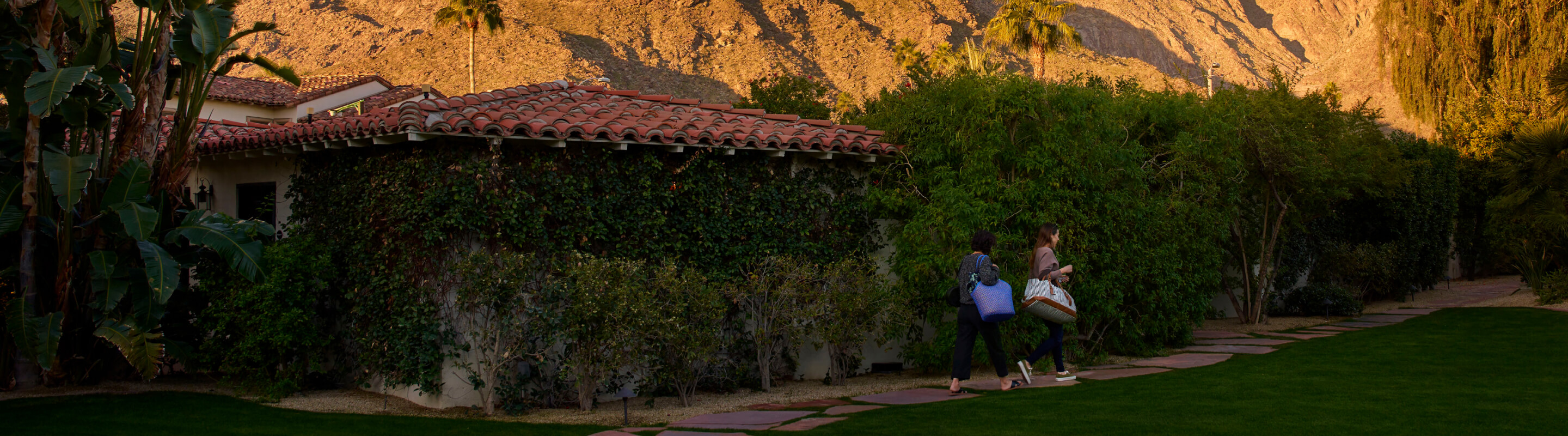 Two people walking on a pathway on the side of a house