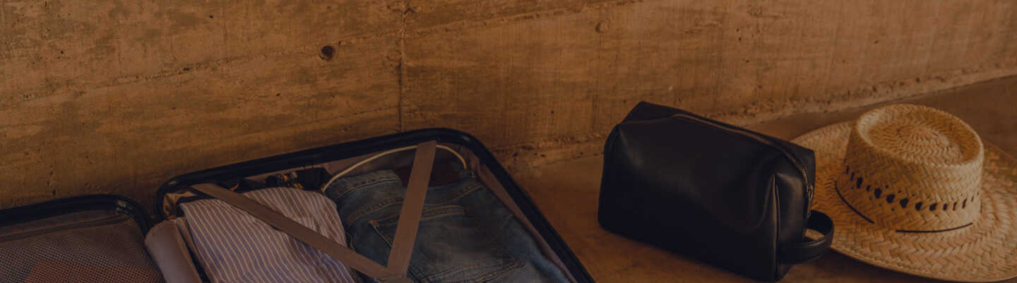 An open suitcase, toiletry bag, and hat are packed for their next trip.