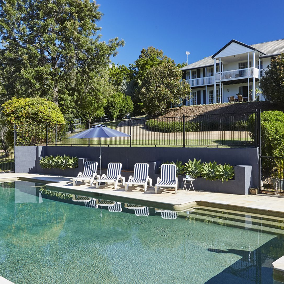 Photograph of a Hampton style house with a pool