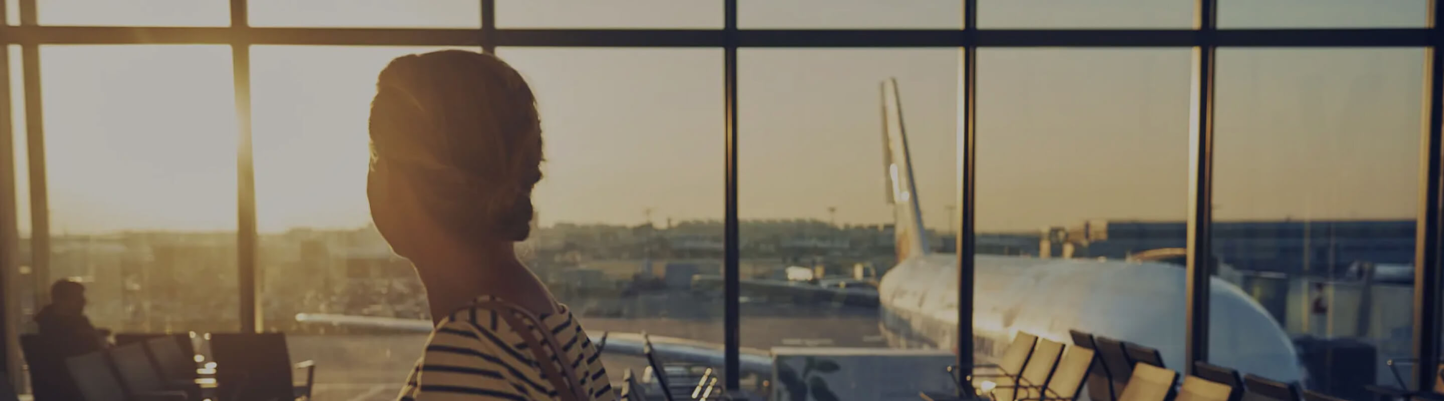 A woman looks out an airport window at waiting planes