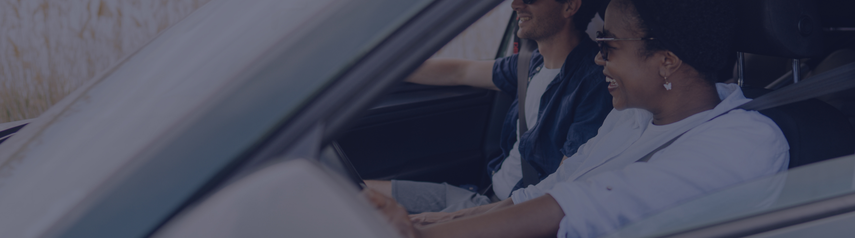 A woman and man laughing while in a car.