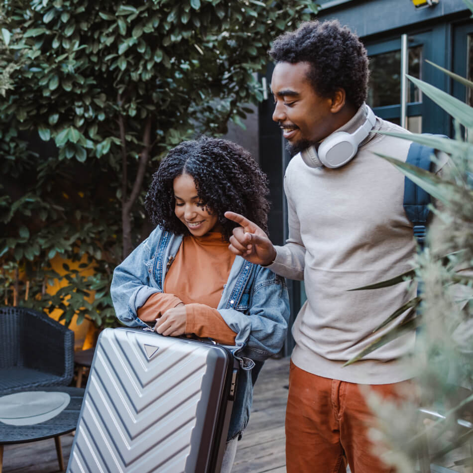 A couple smiling while holding their luggage
