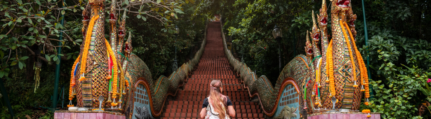 A traveler walks up the ornate steps of Doi Suthep template, Thailand.