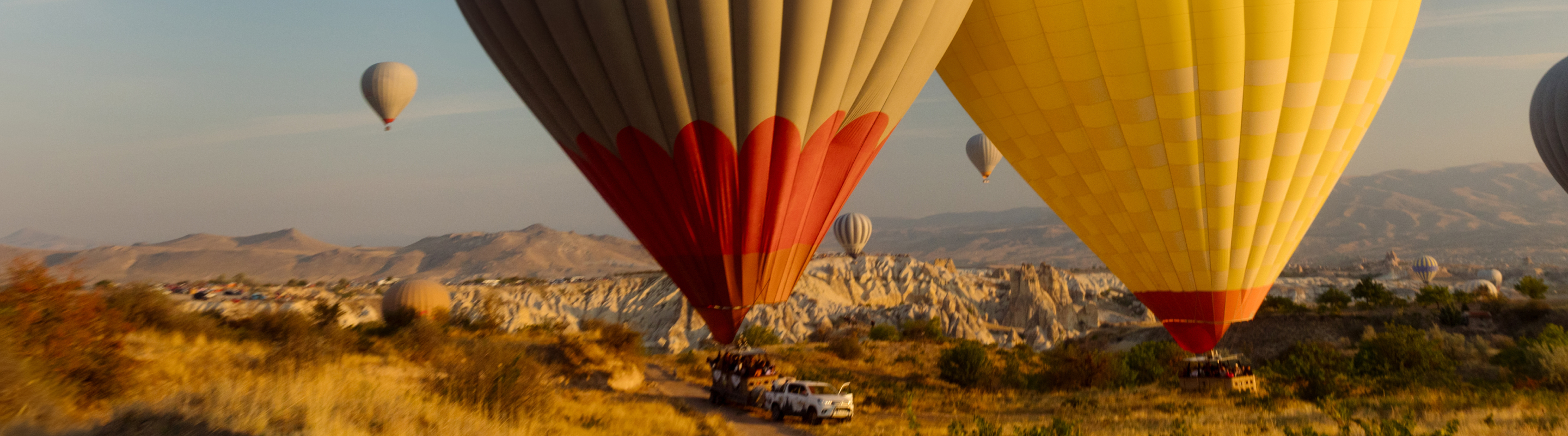Hot air balloons floating over a rocky landscape at sunrise.