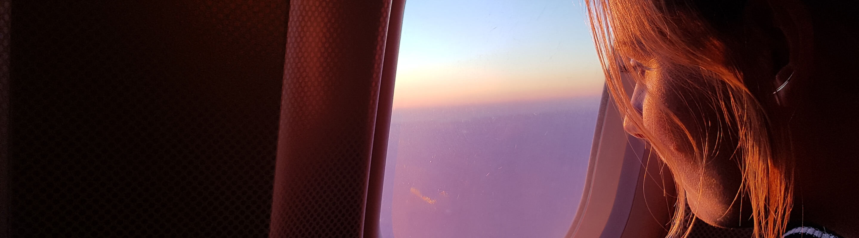 A woman looking out of the window of an airplane while in transit