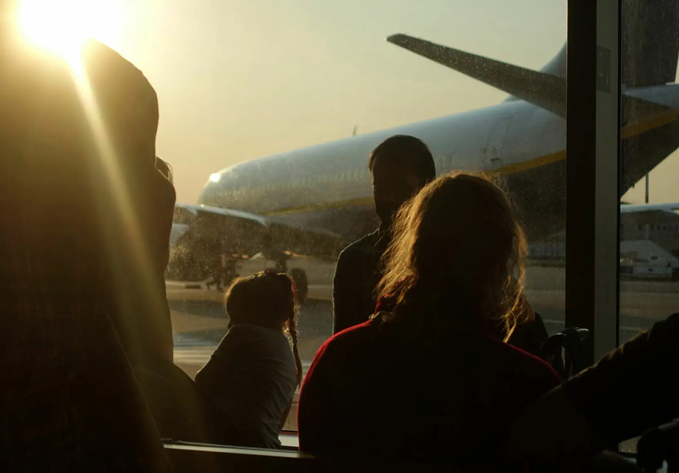 Personnes attendant l’embarquement à l’aéroport avec un beau soleil qui brille à travers la vitre