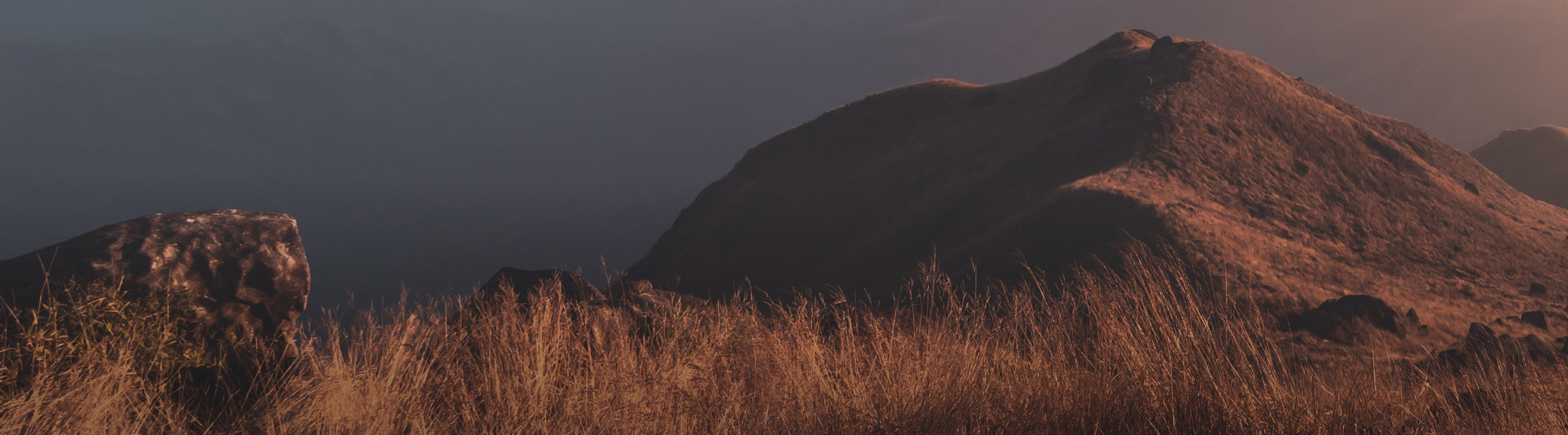 Hilltop over a hazy mountain range at sunrise.