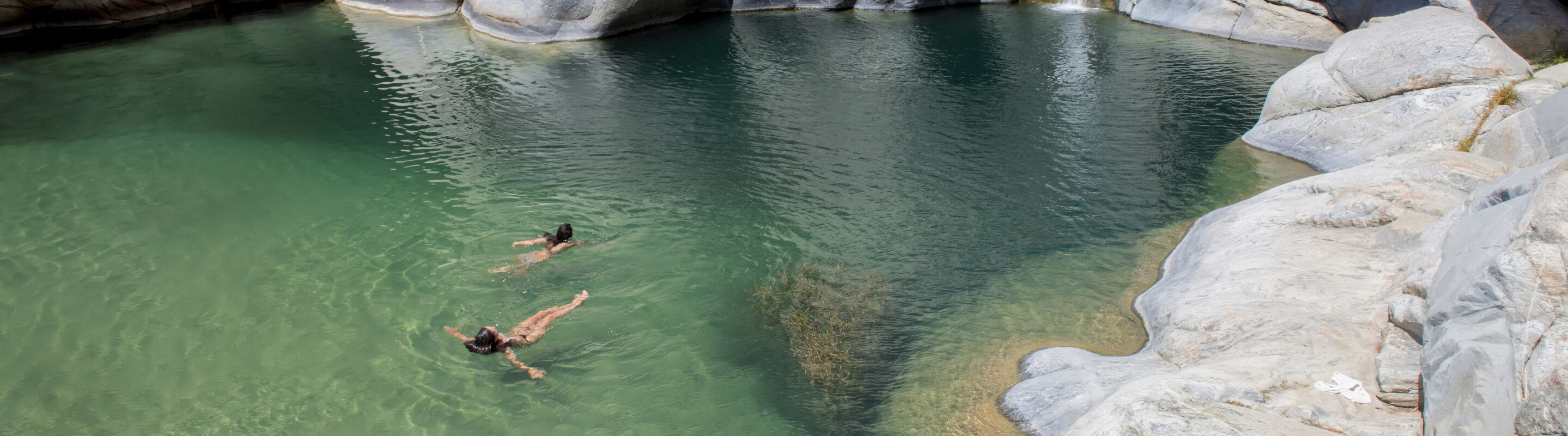 Two people floating in a natural swimming hole